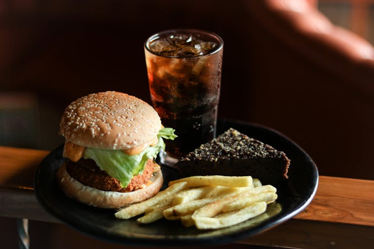 A tasty fast food meal with burger, fries, brownie, and a cold drink.