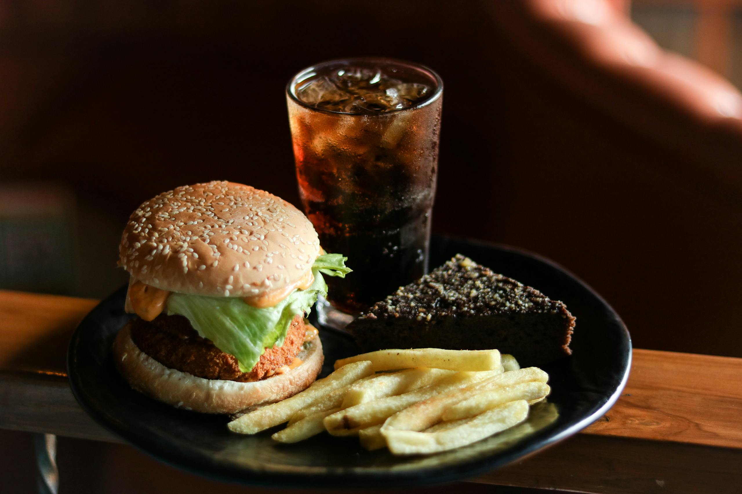A tasty fast food meal with burger, fries, brownie, and a cold drink.
