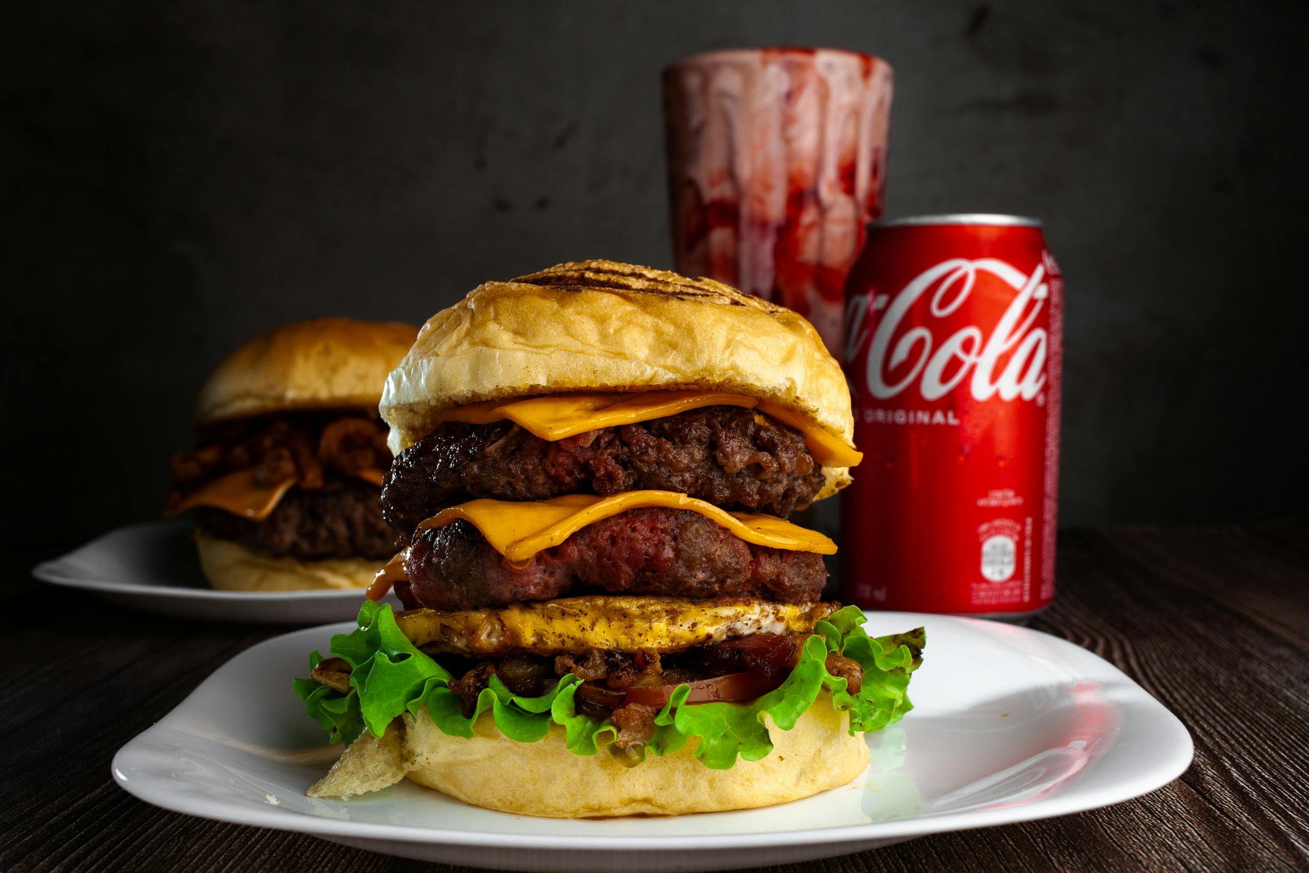 Delicious beef burger with cheese accompanied by a can of Coca Cola.