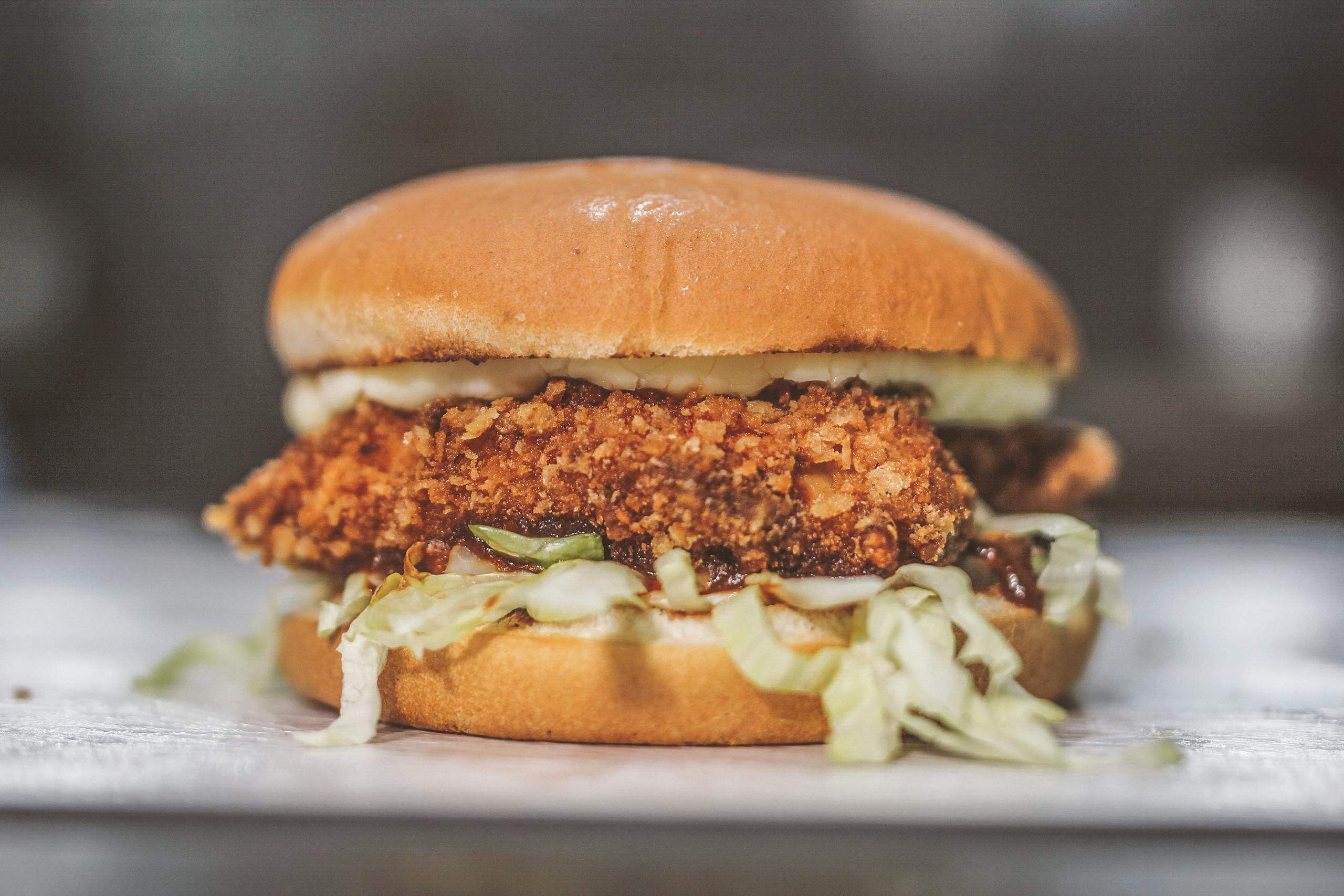 Delicious crispy chicken sandwich with lettuce and sauce served on a bun.