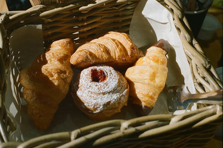 Delicious assortment of croissants and pastries in a wicker basket, perfect for breakfast or a sweet treat.