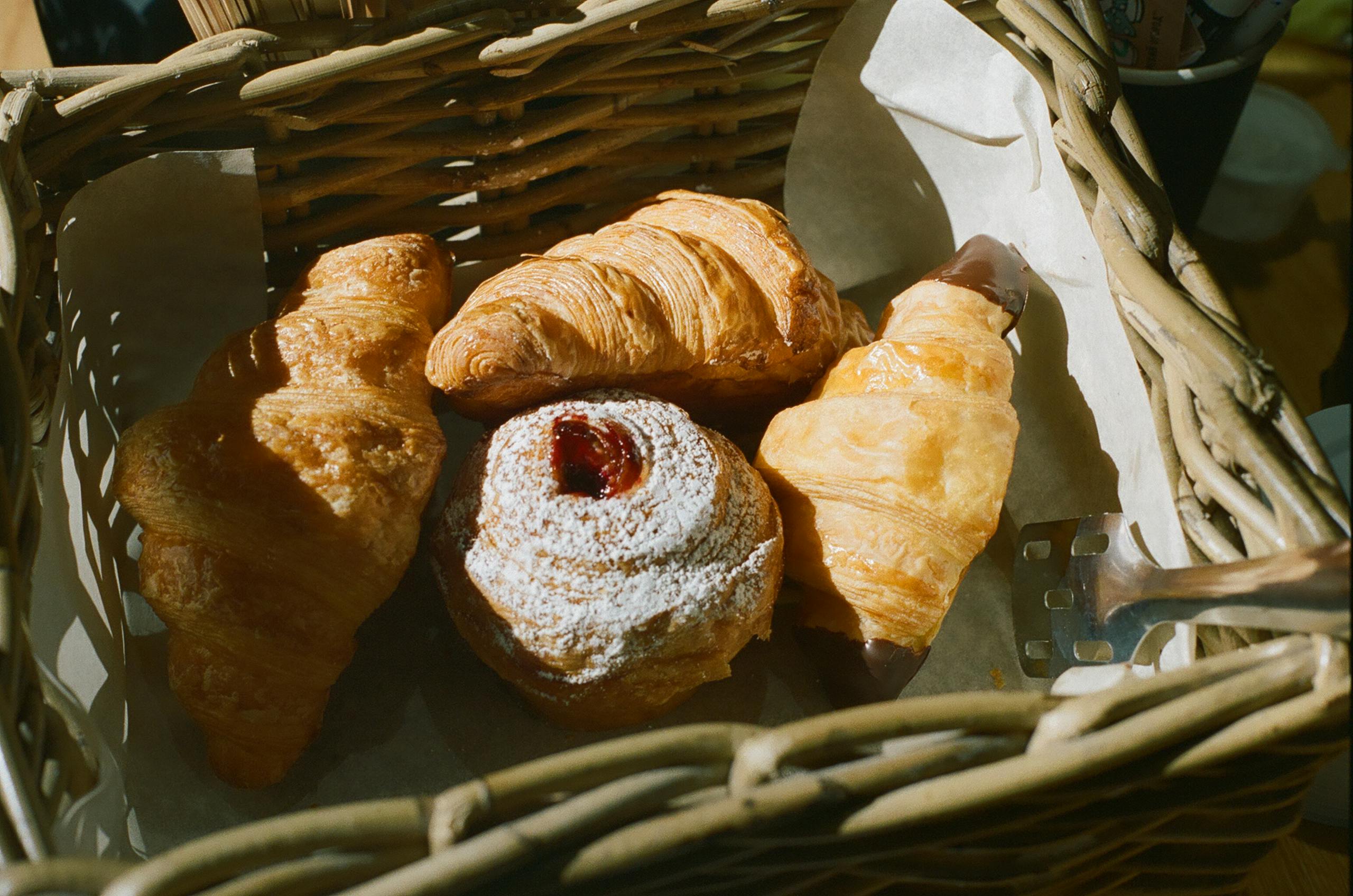 Delicious assortment of croissants and pastries in a wicker basket, perfect for breakfast or a sweet treat.